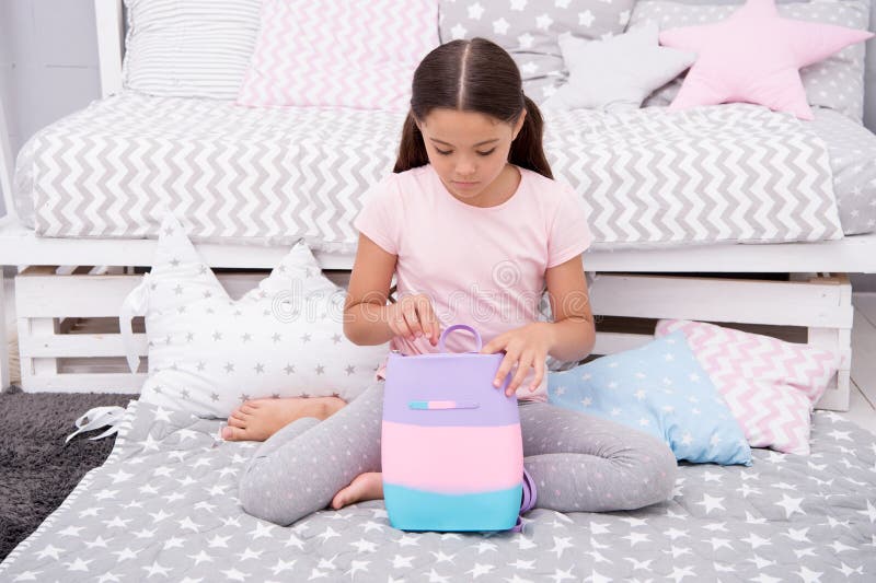 Prepare o saco para amanhã A criança da menina senta-se na cama com saco ou os cosméticos ensacam em seu quarto A criança prepara imagem de stock royalty free Prepare o saco para amanhã A criança da menina senta-se na cama com saco ou os cosméticos ensacam em seu quarto A criança prepara imagem de stock royalty free