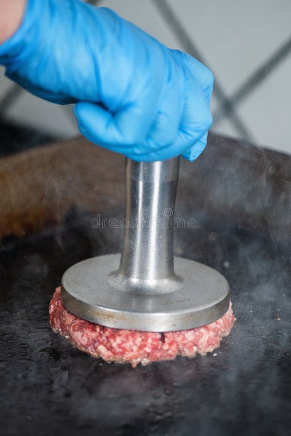 Preparing Burger Patties on the Grill Using Burger Smasher Stock Photo