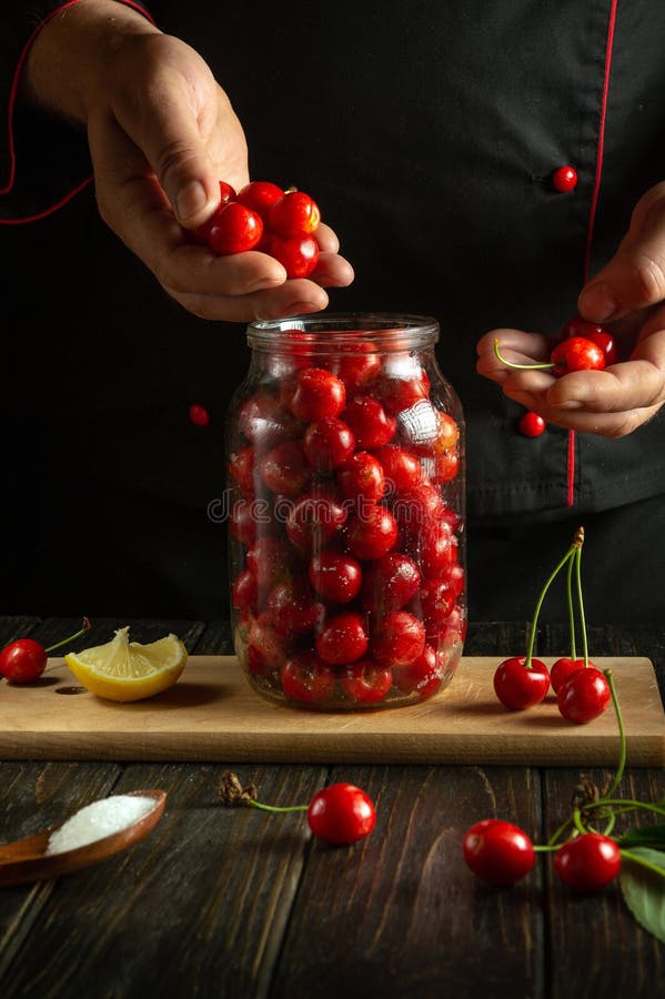 Preparing canned cherries in a jar. A cook prepares sweet cherry for canning on a kitchen table stock photos
