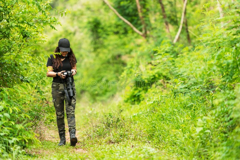 Presa del fotografo della donna professionale all'aperto con la lente principale nella natura verde della foresta pluviale della immagini stock Presa del fotografo della donna professionale all'aperto con la lente principale nella natura verde della foresta pluviale della immagini stock