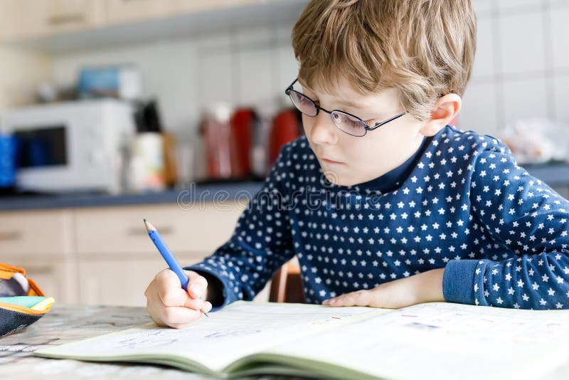 Preschool kid boy at home making homework writing letters with colorful pens