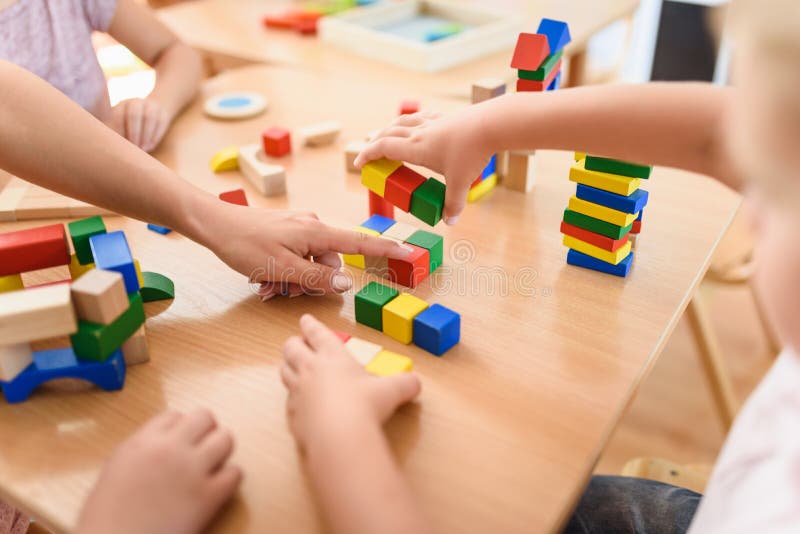 Preschool nauczyciel z dziećmi bawić się z kolorowymi drewnianymi dydaktycznymi zabawkami przy dziecinem zdjęcia royalty free