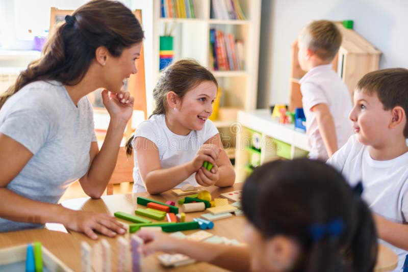 Preschool teacher with children playing with colorful didactic toys at kindergarten