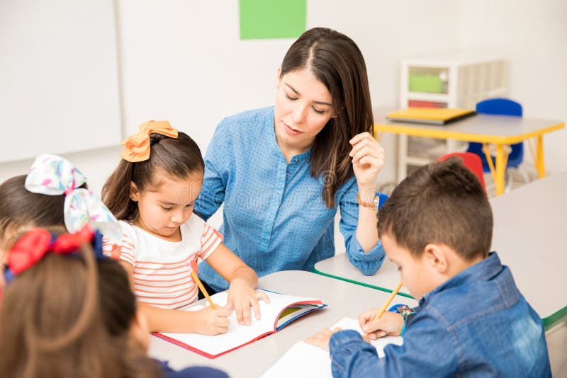 Preschool teacher helping her pupils royalty free stock photography Preschool teacher helping her pupils royalty free stock photography