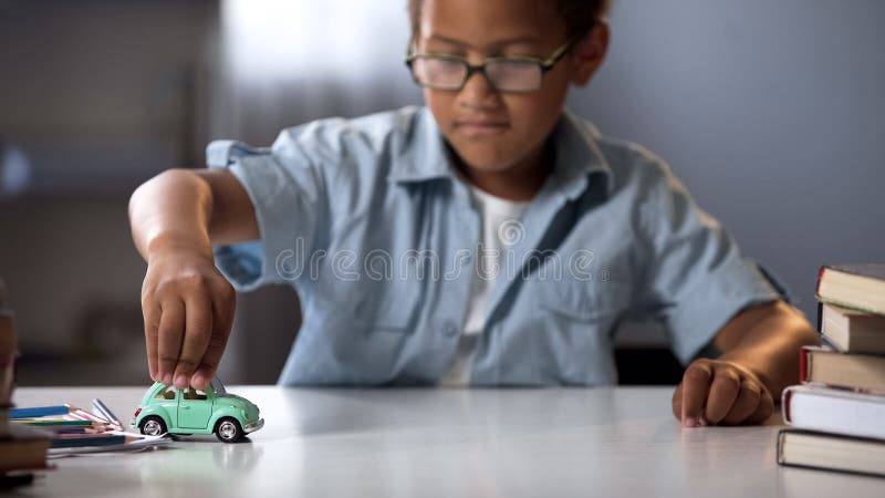 Preschooler boy playing with toy car, dreaming about real auto and traveling