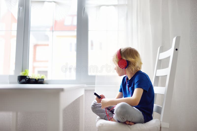 Preschooler child enjoy listen music or audiobook using his headphones at home