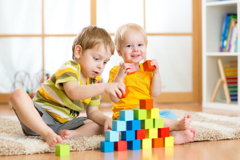 Preschooler children playing with colorful toy blocks. Kid playing with educational wooden toys at kindergarten or day care center