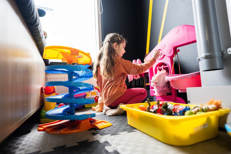 Preschooler girl child in day care center playing with dolls toys