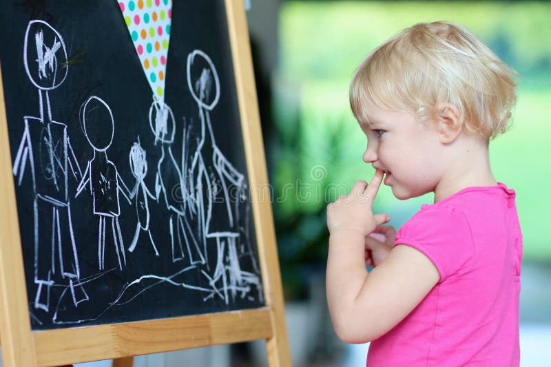 Preschooler girl drawing on black board