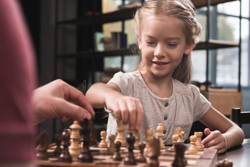 Preschooler kid playing chess with her father