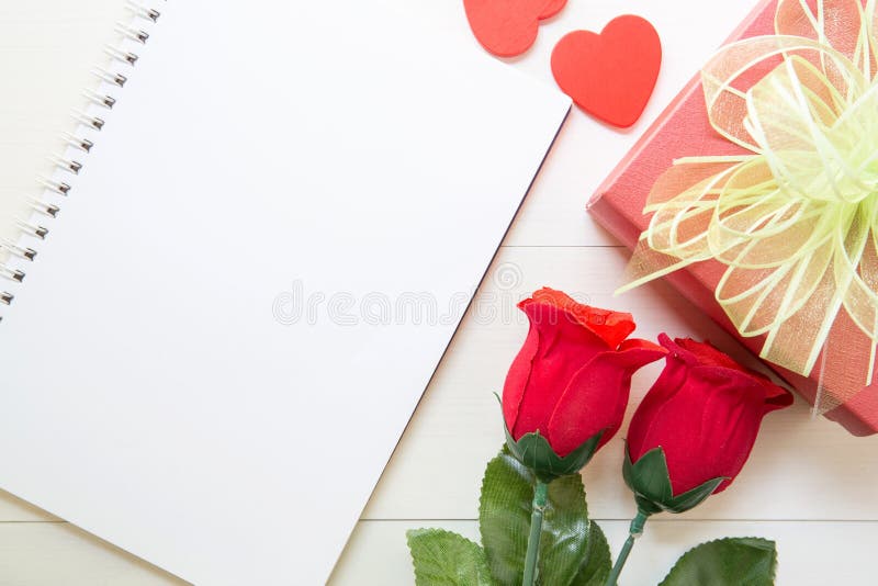 Present red rose flower and notebook and gift box and heart shape with copy space on wooden table