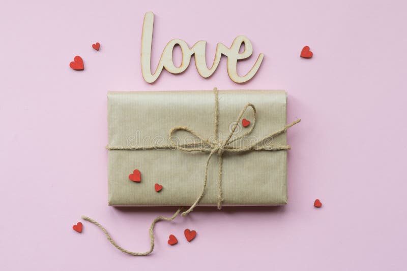 Present wrapped in brown craft paper and tie hemp string on Light pink background. Romantic Gift with decorative red stock image Present wrapped in brown craft paper and tie hemp string on Light pink background. Romantic Gift with decorative red stock image