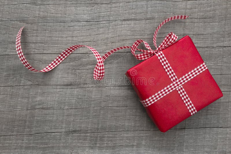 Present wrapped in red paper on a wooden background, checkered ribbon stock photos Present wrapped in red paper on a wooden background, checkered ribbon stock photos