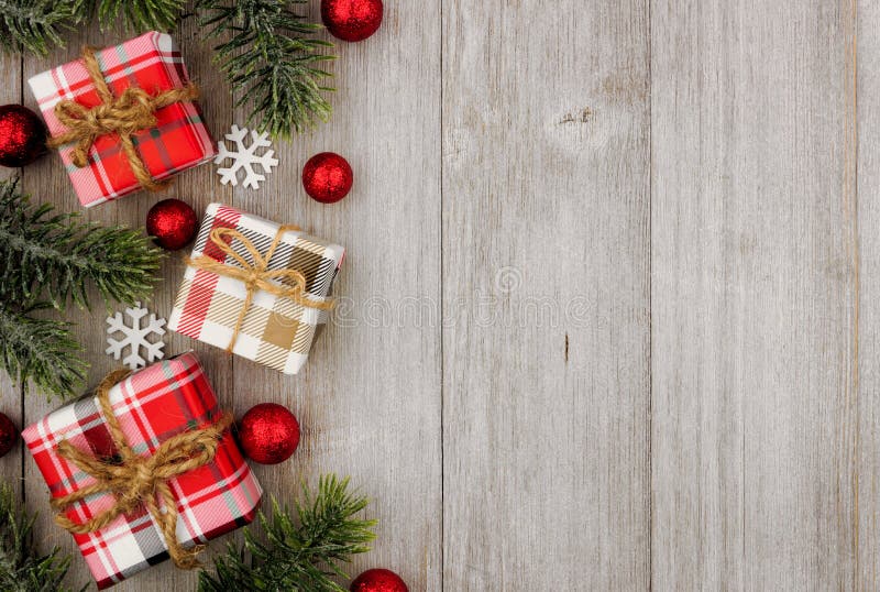 Presentes da beira do Natal e ramos de árvore laterais na madeira cinzenta