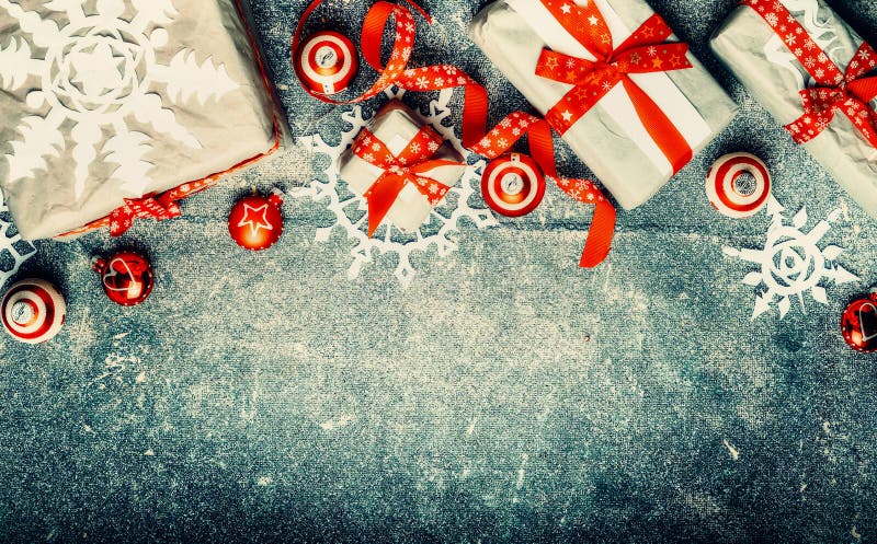 Presentes do Natal, decorações festivas vermelhas do feriado e flocos de neve de papel no fundo do vintage, vista superior