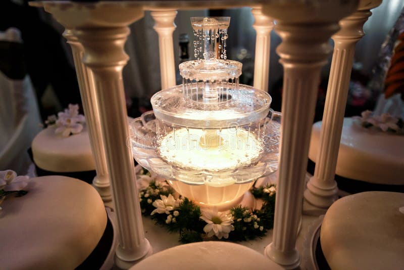 Presenti la decorazione della fontana del champagne in luce e torta nunziale fotografia stock libera da diritti Presenti la decorazione della fontana del champagne in luce e torta nunziale fotografia stock libera da diritti