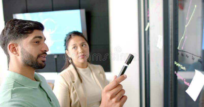 Presenting data on whiteboard, colleagues discussing business strategy in office stock video