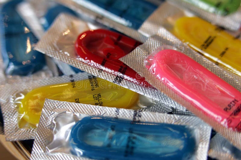 Preservativos coloridos em uns pacotes da folha de modo operacional