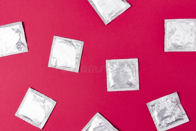 Preservativos no fundo cor-de-rosa Conceito da contracepção e do sexo seguro Proteção do VIH durante relações sexuais