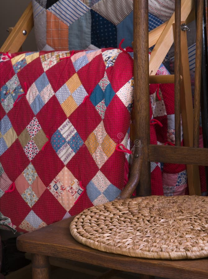 View of antique kitchen chair with rush pad, and antique quilts hanging on a rack. View of antique kitchen chair with rush pad, and antique quilts hanging on a rack.