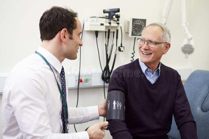 Presión arterial del doctor Taking Senior Patient en hospital foto de archivo libre de regalías Presión arterial del doctor Taking Senior Patient en hospital foto de archivo libre de regalías