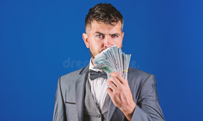Prestiti di contanti facili Mucchio convenzionale della tenuta del vestito dell'uomo del fondo blu delle banconote del dollaro L' immagini stock libere da diritti Prestiti di contanti facili Mucchio convenzionale della tenuta del vestito dell'uomo del fondo blu delle banconote del dollaro L' immagini stock libere da diritti