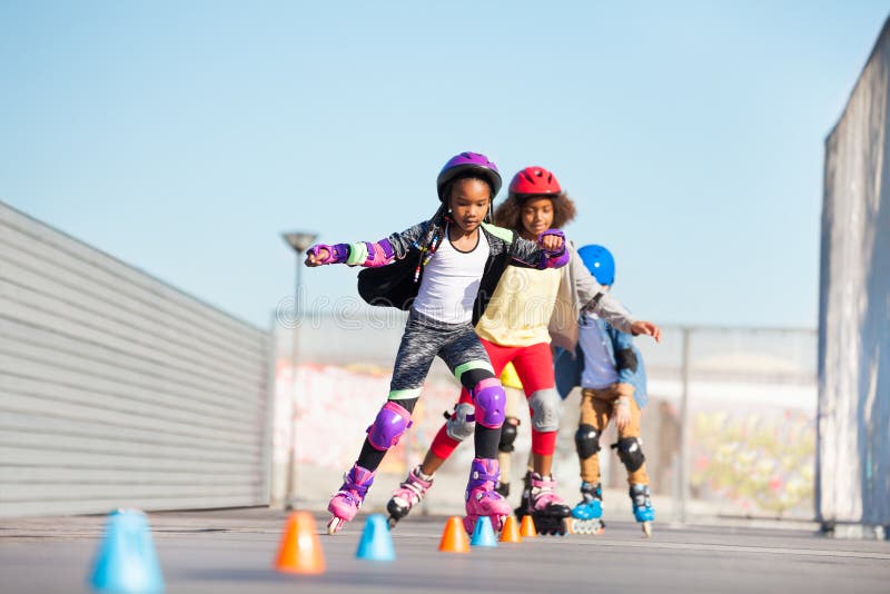 Preteen African girls, inline skaters, doing tricks at skate park in summer. Preteen African girls, inline skaters, doing tricks at skate park in summer