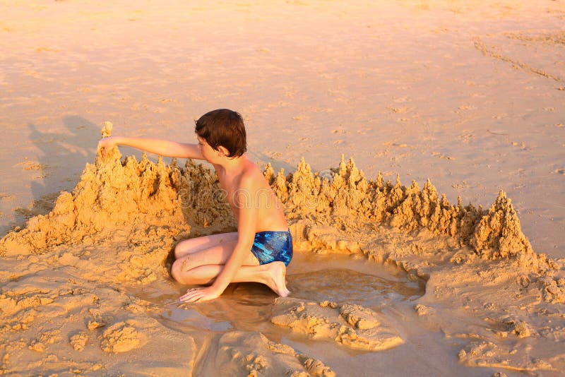 Preteen boy playing with sand on the beach