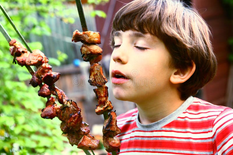 Preteen boy smell shashlik meat on summer picnic