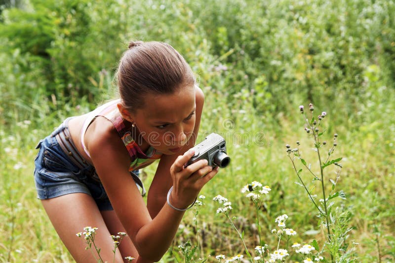 Preteen girl making pictures with digital camera on green grass background outdoors. Preteen girl making pictures with digital camera on green grass background outdoors