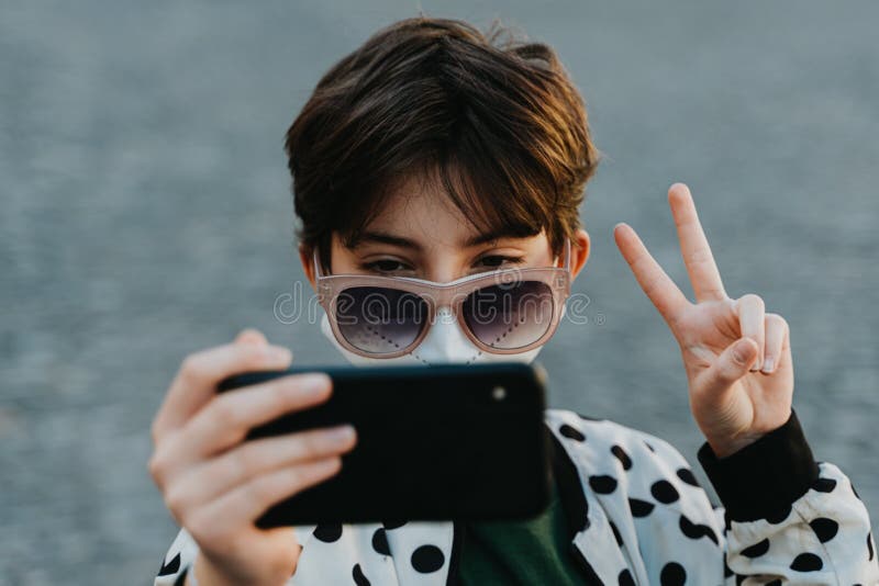 Preteen girl en lunettes de soleil prenant selfie pour les réseaux sociaux en dehors de la ville concept coronavirus. images stock