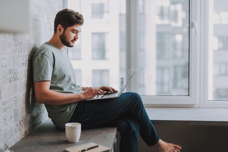 Prettige gebaarde mens die zijn laptop thuis met behulp van stock afbeeldingen Prettige gebaarde mens die zijn laptop thuis met behulp van stock afbeeldingen