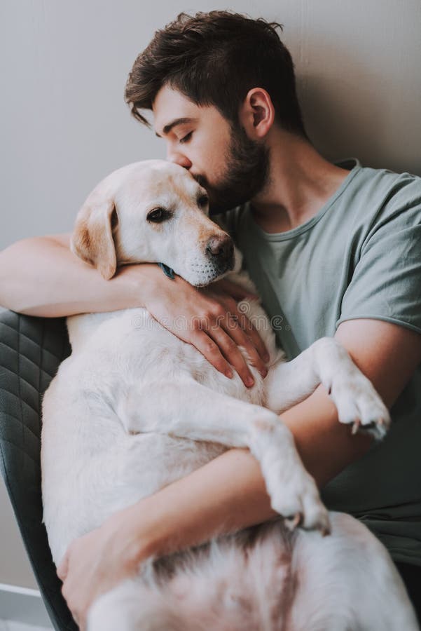 Prettige jonge mens die zijn hond kussen terwijl het uitdrukken van liefde stock foto Prettige jonge mens die zijn hond kussen terwijl het uitdrukken van liefde stock foto