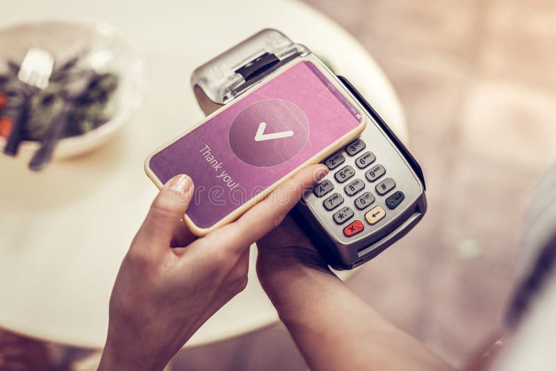 Prettige jonge vrouw die haar smartphone voor betaling gebruiken royalty-vrije stock foto's Prettige jonge vrouw die haar smartphone voor betaling gebruiken royalty-vrije stock foto's