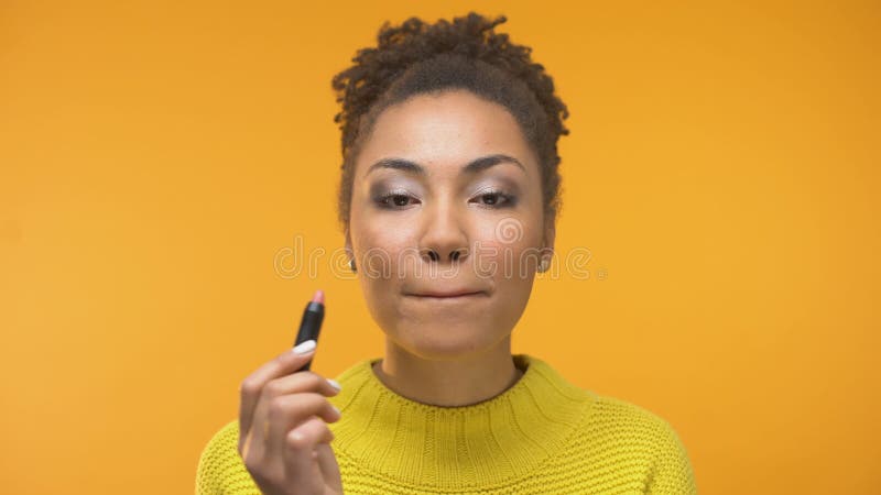 Pretty African-American girl applying lipstick and winking, ready for date