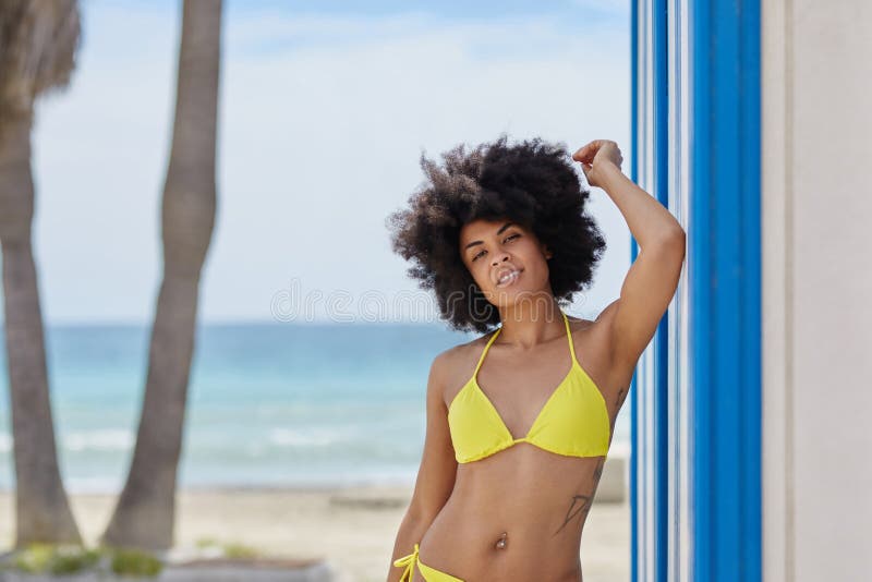 Portrait of pretty afro american woman in bikini standing on beach