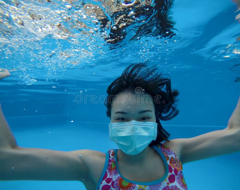 Pretty asian woman swimming under blue water with protective face mask and smiling eyes royalty free stock images Pretty asian woman swimming under blue water with protective face mask and smiling eyes royalty free stock images