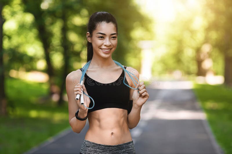 Pretty Athletic Asian Girl Exercising With Skipping Rope In Morning Park, Training Outdoors, Free Space. Pretty Athletic Asian Girl Exercising With Skipping Rope In Morning Park, Training Outdoors, Free Space