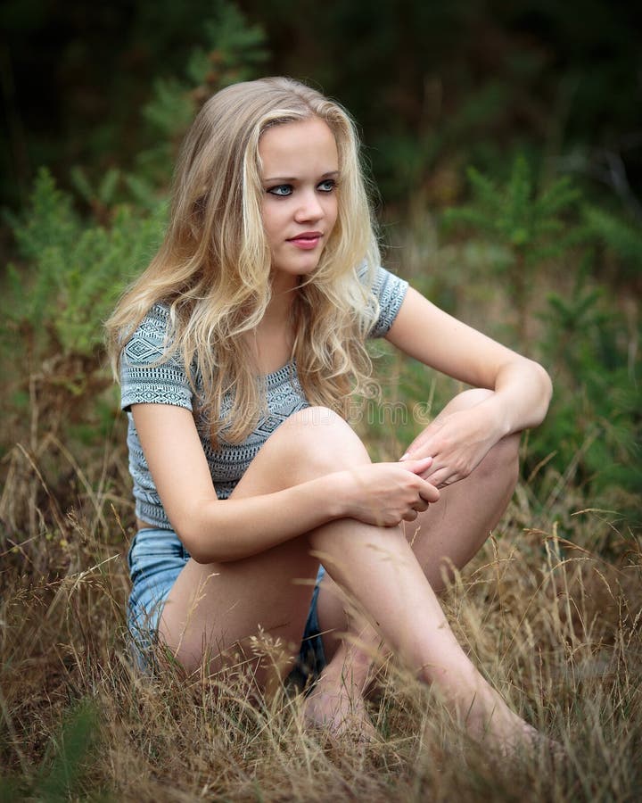 Pretty Blond Teenager Sitting In The Grass Stock Image