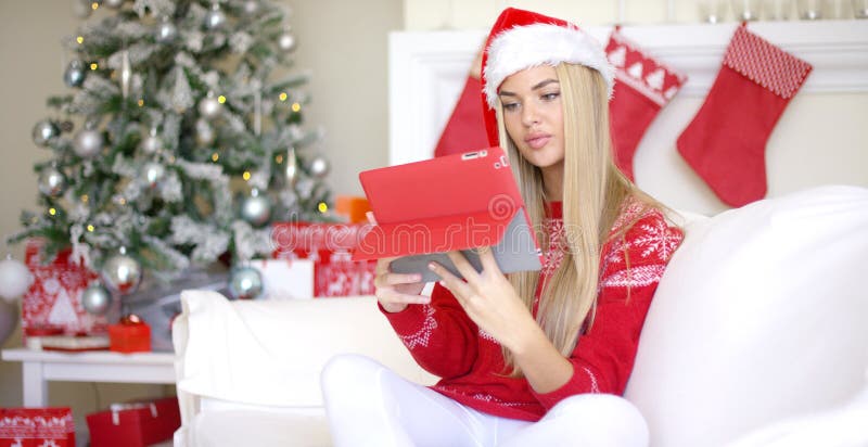 Pretty blond young woman sitting on couch with touchpad
