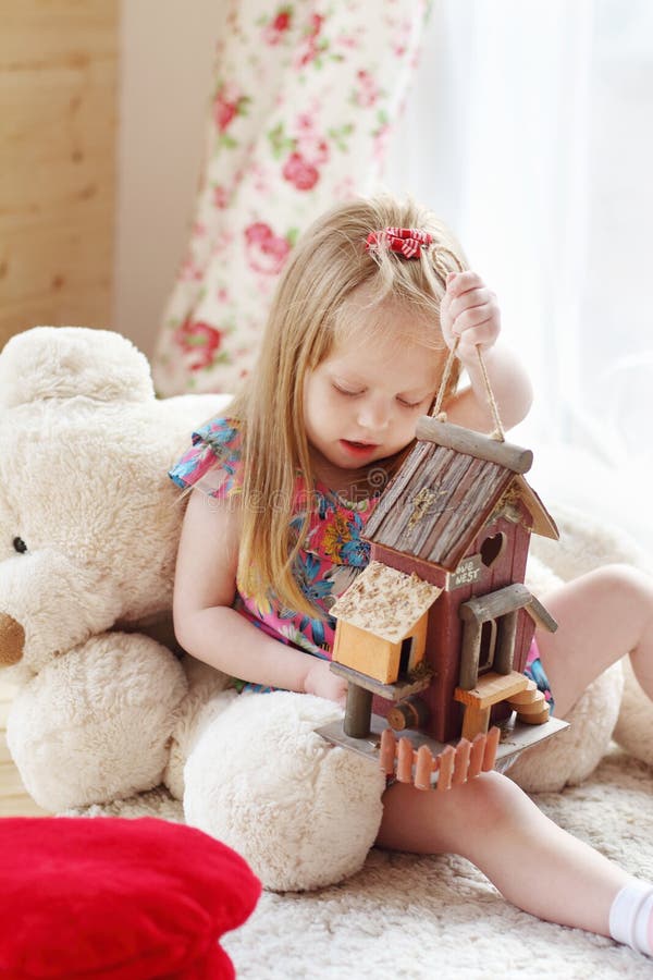 Pretty blonde little girl sits on carpet near window