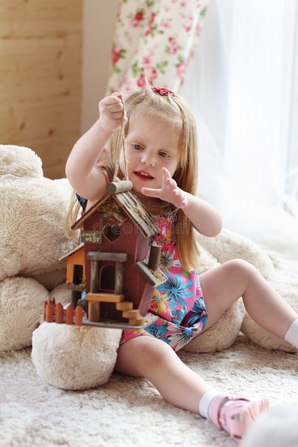 Pretty blonde little girl sits on carpet near window