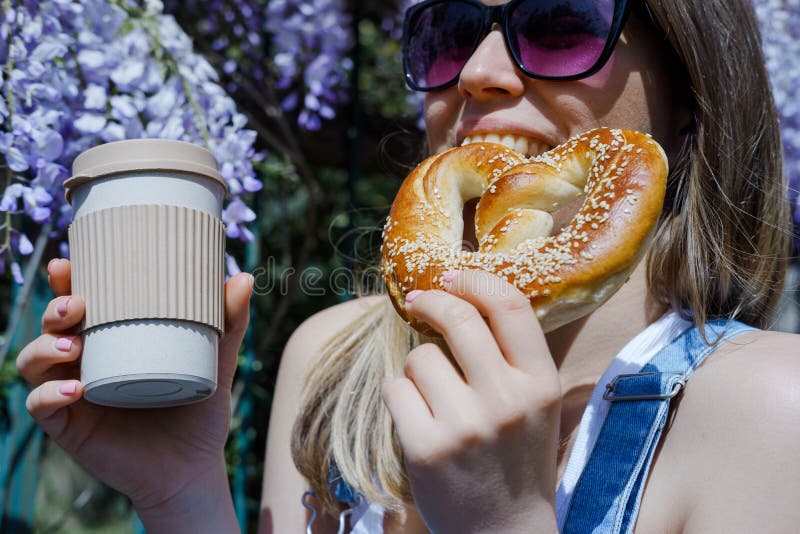 Pretty blonde woman holding cup of coffee and sweet pretzel in a stock photos Pretty blonde woman holding cup of coffee and sweet pretzel in a stock photos