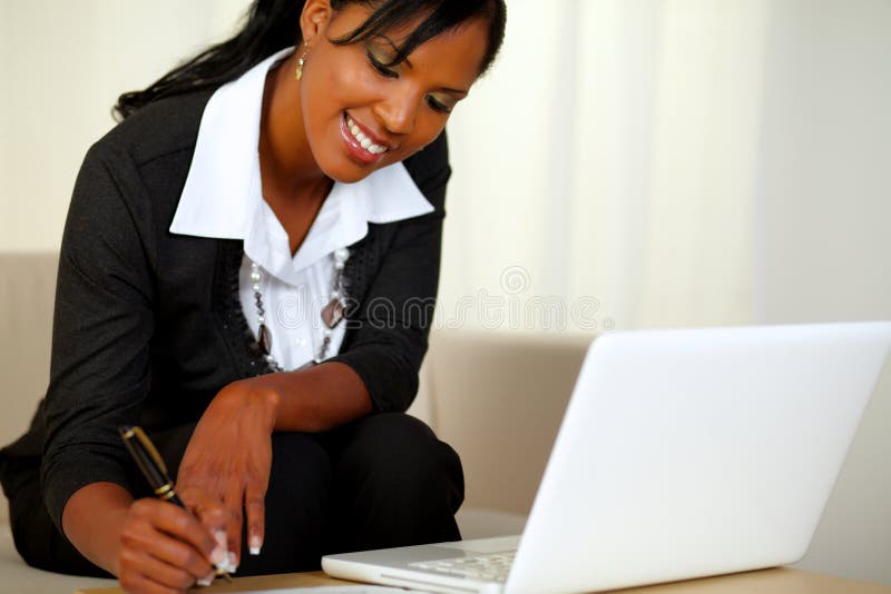 Portrait of a pretty businesswoman on black suit working while sitting on couch in front of her laptop