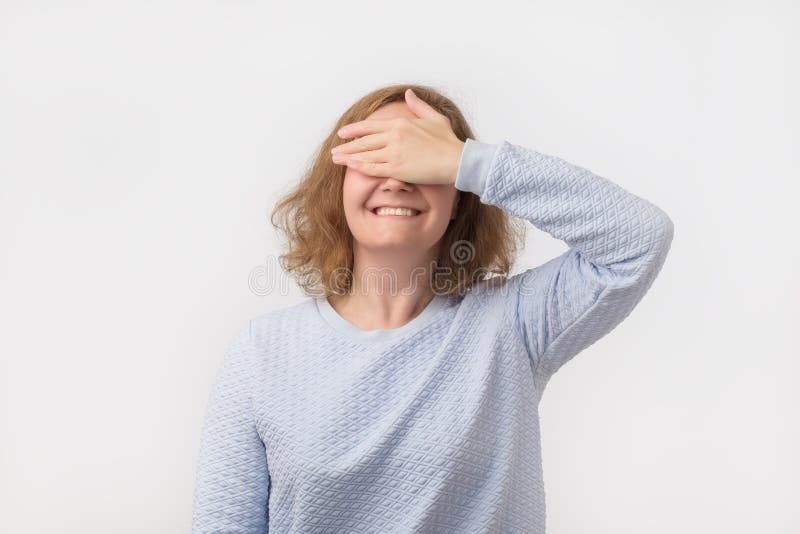 Pretty european girl in blue sweater closing her eyes with hand, having happy expression royalty free stock photography Pretty european girl in blue sweater closing her eyes with hand, having happy expression royalty free stock photography
