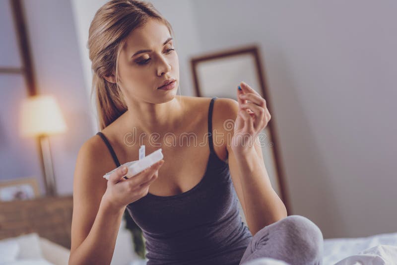 Pretty fair-haired woman scrutinizing analgesic capsule