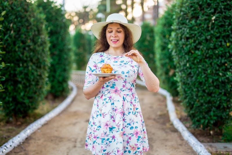 Pretty funny woman eating the cake in the park. Food, diet, unhealthy food and sweet concept. Sugar addiction.