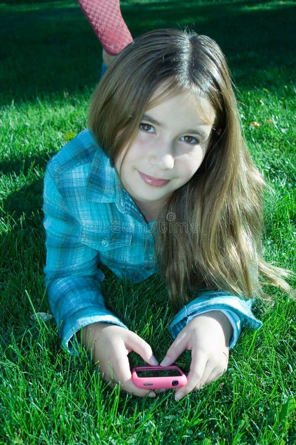 Pretty girl with cell phone laying on grass