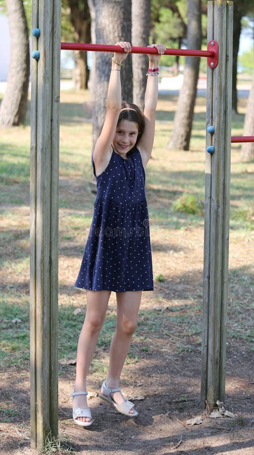 Pretty girl does gymnastics on the playground with blue dress