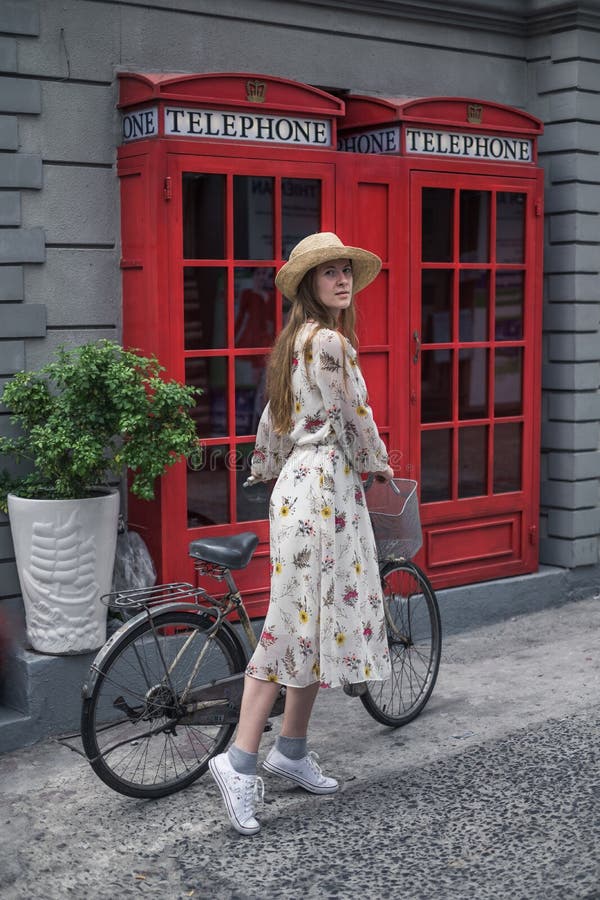 Caucasian hipster girl in dress, sneakers and straw hat standing